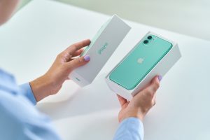 Femme ouvrant une boîte contenant un iPhone de couleur bleu vert